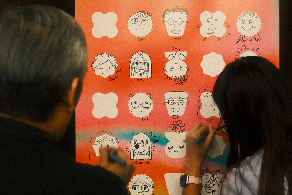 people drawing portraits on orange wall